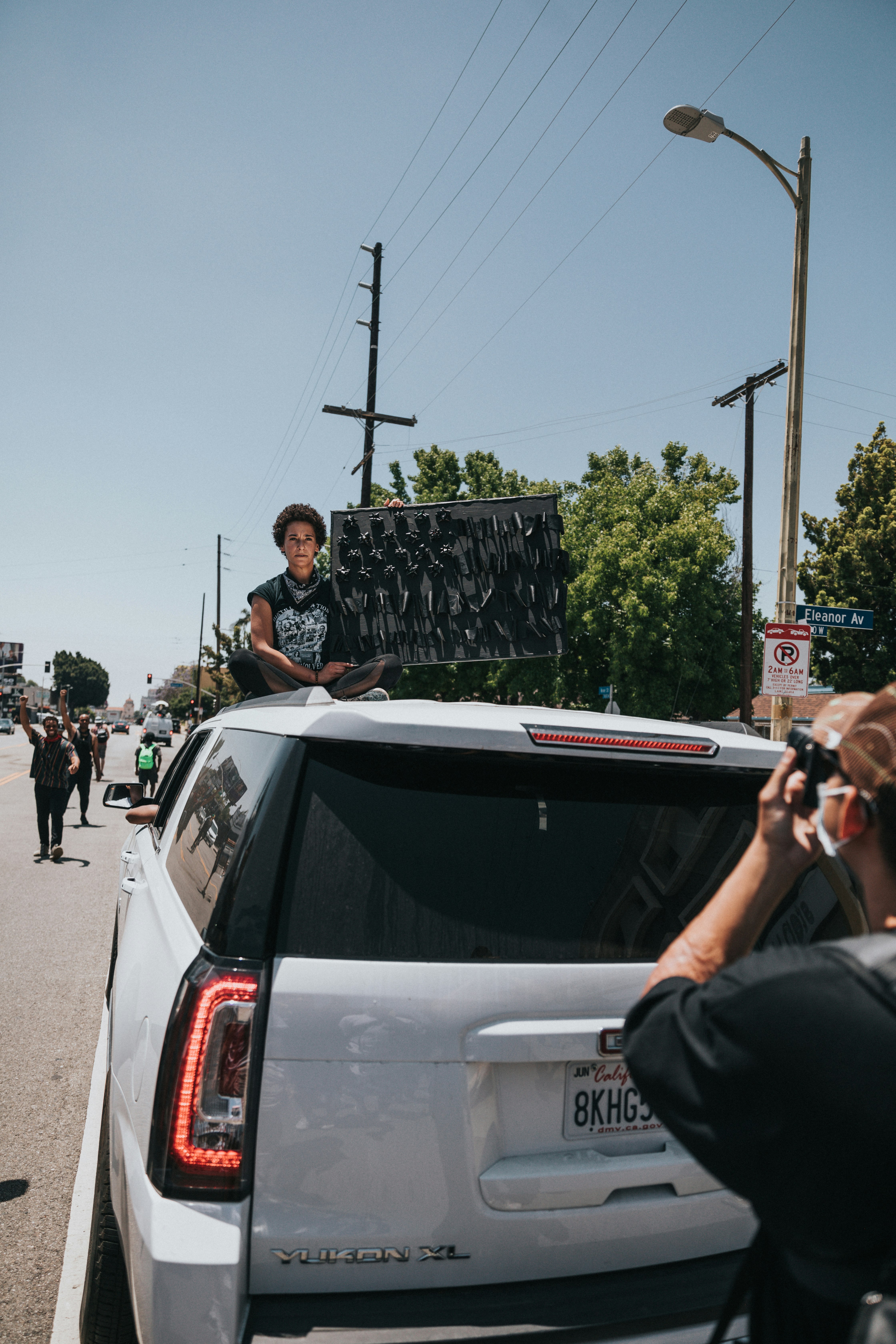 man in black t-shirt and black pants sitting on white car hood during daytime